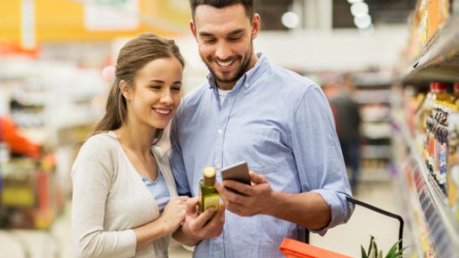 couple grocery shopping in aisle with smartphone